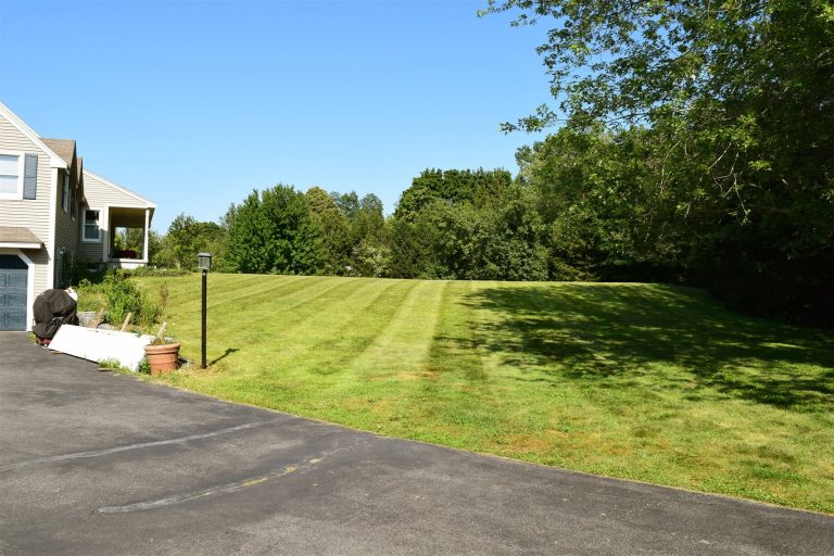 Manicured side lawn with mowing stripes alongside a paved driveway - RN Land Management